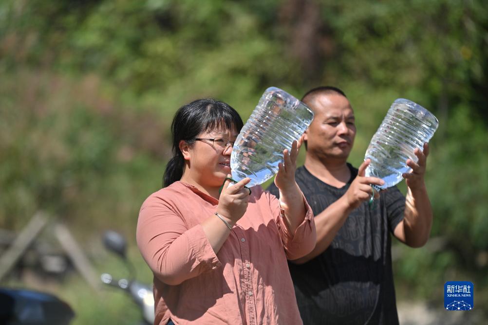 楊寧（左）在查看村民剛剛采集的水樣，為山泉水引水工程做準(zhǔn)備（10月8日攝）。新華社記者 黃孝邦 攝